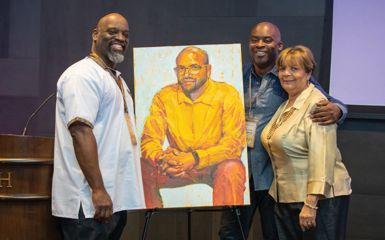 Three people posing with portrait of Sterling Ashby